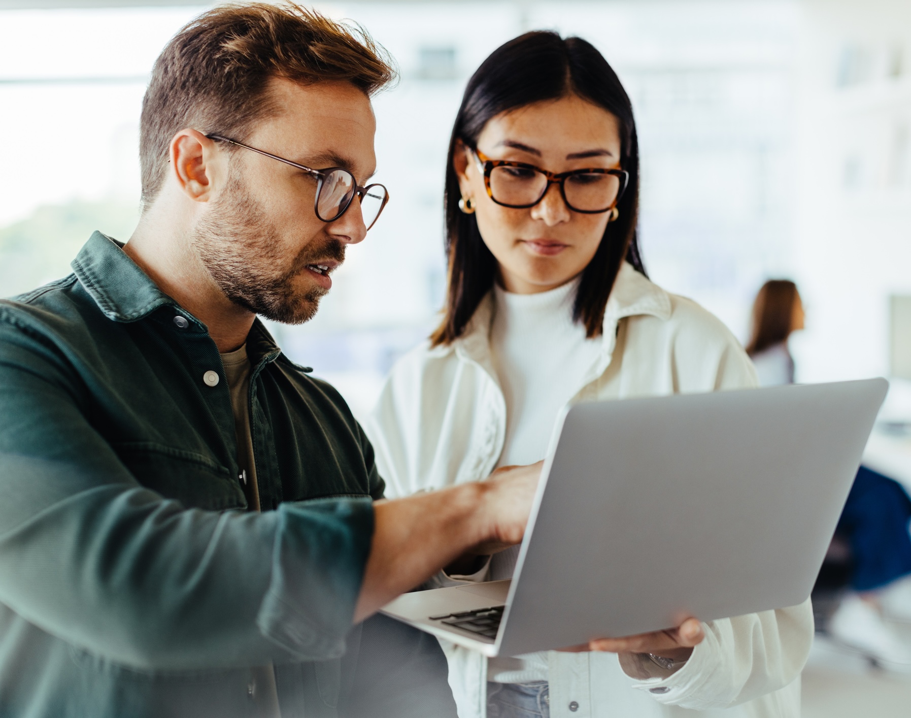 Two people talking and looking at a laptop