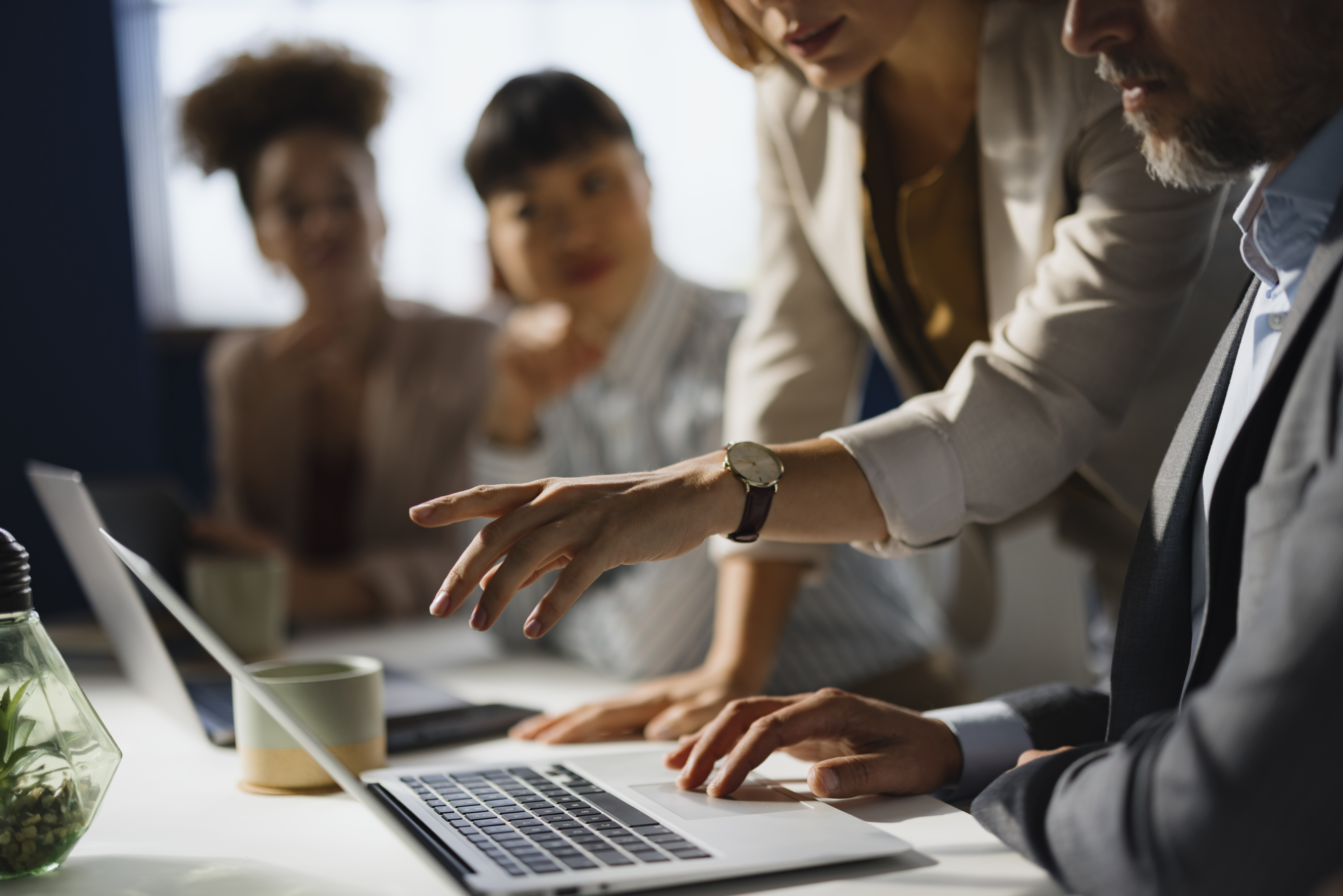 Four coworkers collaborating around a laptop