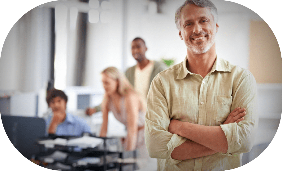 A man smiling with a meeting happening in the background