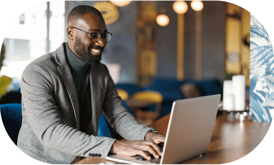 A man smiling and typing on a laptop